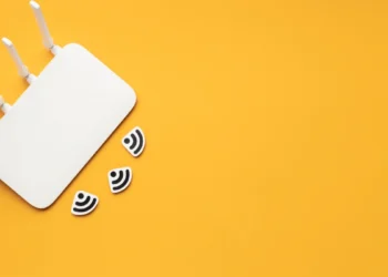 Roteador de quatro antenas sobre superfície amarela. Sinais de Wi-Fi espalhados em torno dele. Falando sobre Wi-Fi para casa inteligente.