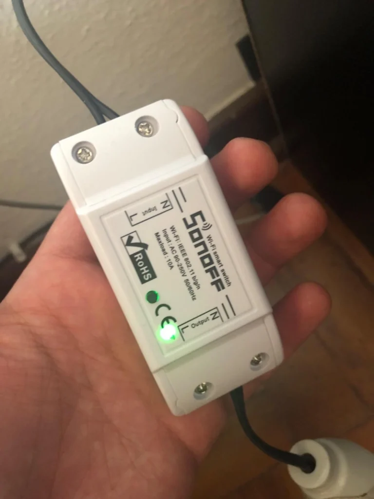 Pessoa com um exemplar de Sonoff TX Ultimate em mãos. Falando sobre o melhor interruptor inteligente.